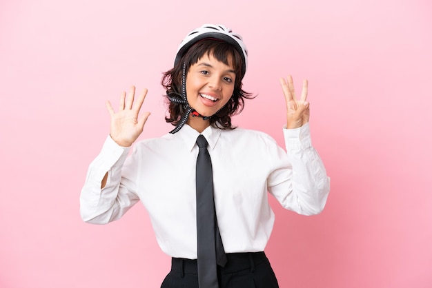 Persona joven con un casco de bicicleta aislado sobre fondo rosa contando ocho con los dedos