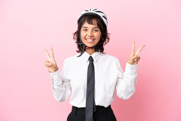 Persona joven con un casco de bicicleta aislado sobre fondo rosa mostrando el signo de la victoria con ambas manos