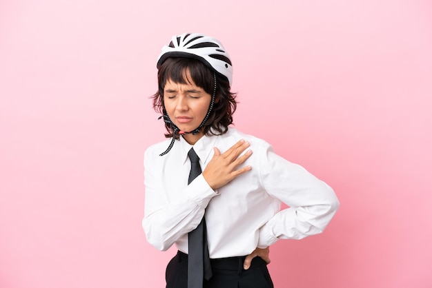 Persona joven con un casco de bicicleta aislado sobre fondo rosa que sufre de dolor en el hombro por haber hecho un esfuerzo