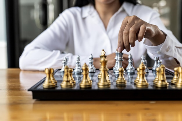 Foto persona jugando al juego de tablero de ajedrez, imagen conceptual de mujer de negocios sosteniendo piezas de ajedrez como competencia comercial y gestión de riesgos, planificando estrategias comerciales para derrotar a los competidores comerciales.