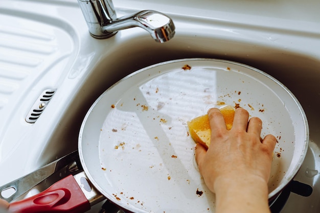 Una persona lavando platos con una esponja.