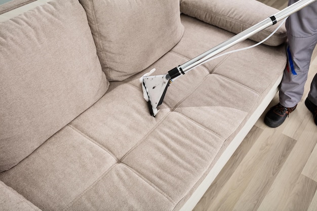 Persona limpiando sofá con aspiradora