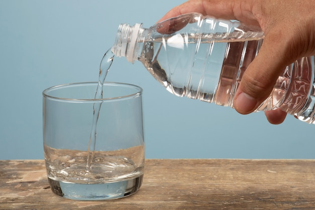 Persona llenando una taza de agua con una botella para mascotas