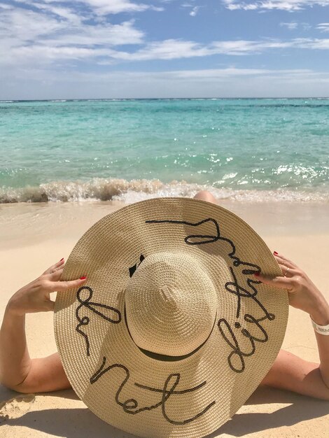 Foto persona con la mano en la arena en la playa contra el cielo