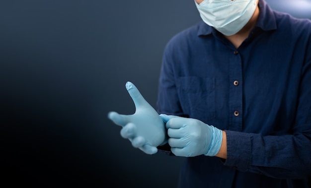 Foto persona con mascarilla quirúrgica en la cara intente usar guantes médicos. mantener limpio y protegido antes de hacer algo.