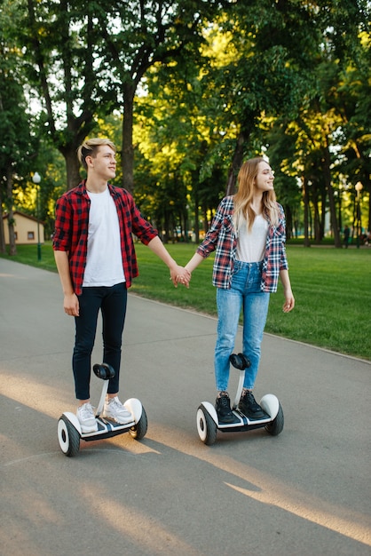 Persona masculina y femenina montando en gyro board en el parque.