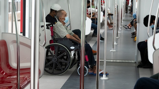Persona mayor discapacitada en silla de ruedas viajando en tren para transporte.