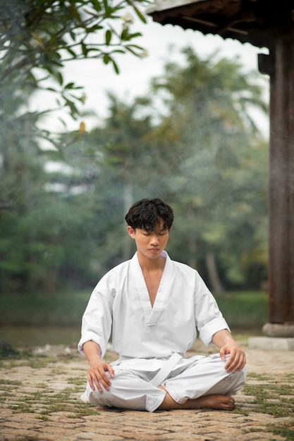 Foto persona meditando antes del entrenamiento de taekwondo