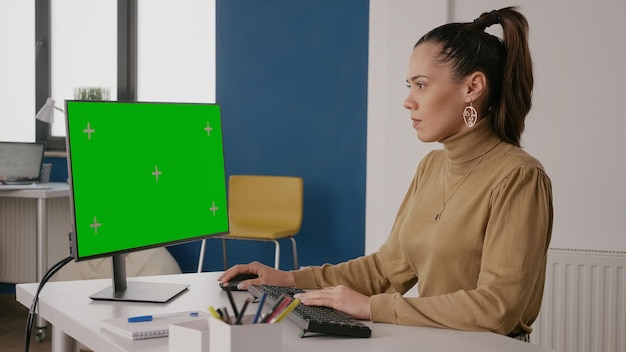 Persona mirando la pantalla verde en la pantalla de la computadora en la oficina, trabajando con una plantilla de maqueta aislada y una clave de croma en un fondo en blanco. Mujer de negocios usando maqueta en pantalla.