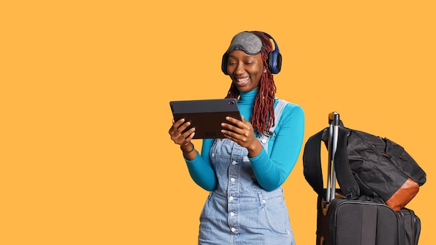 Persona moderna viendo un programa de televisión en una tableta en el estudio, usando auriculares para ver episodios en línea de series de televisión durante el vuelo en avión. Joven turista mirando una película antes de llegar de vacaciones.