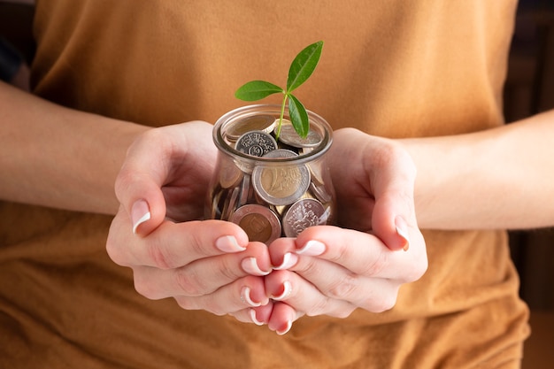 Persona con moneda jarra con planta