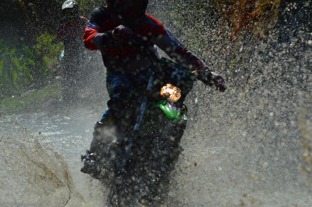 Persona montando motocicletas en una carretera mojada en la ciudad