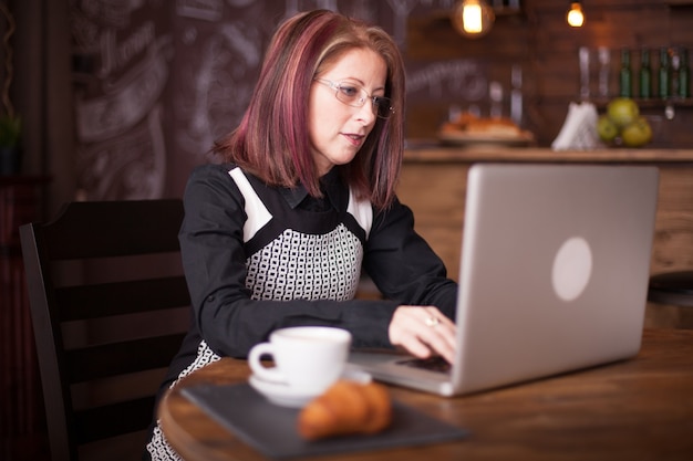 Persona de negocios escribiendo en un cuaderno mientras se sirve un café en la hermosa cafetería vintage