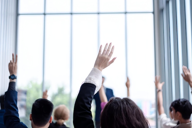 Foto persona de negocios levantando la mano durante el seminario levantando la mano en la conferencia pidiendo responder a una pregunta en la sala de reuniones de negocios y la clase de seminario