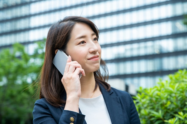 Persona de negocios mujer asiática contactando utilizando un martphone al aire libre