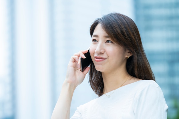 Persona de negocios mujer asiática contactando utilizando un martphone al aire libre