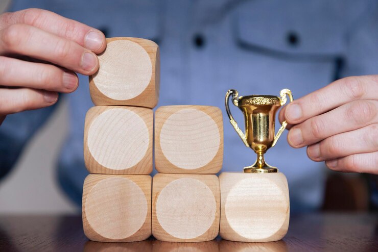 Persona de negocios que arregla grandes bloques de madera con un trofeo ganador éxito comercial
