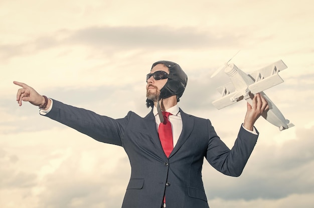 Foto persona de negocios en traje y sombrero de piloto juguete de avión de lanzamiento