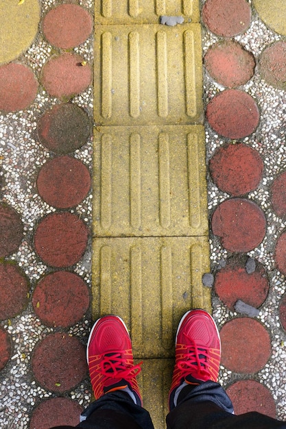 Una persona parada en una acera con zapatos rojos.