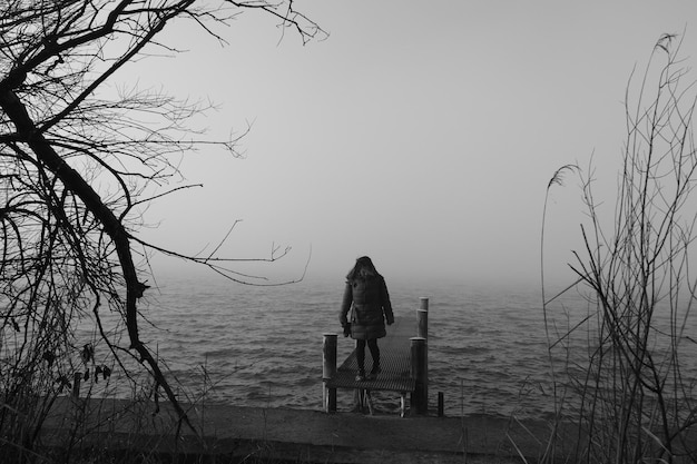 Foto una persona de pie con la cabeza inclinada hacia el lago