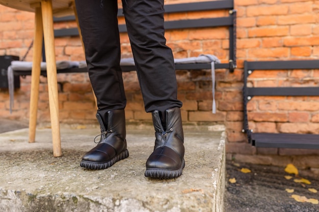 Una persona de pie en un escalón con botas de cuero negro.