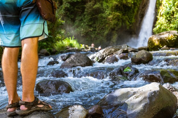 Persona de pie junto a un río frente a una cascada. Turrialba, Costa Rica