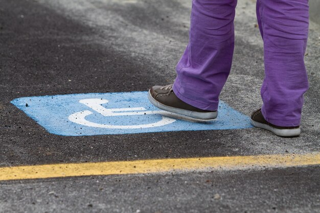 Persona pisando un cartel de estacionamiento reservado para discapacitados