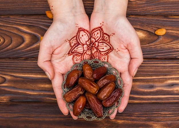 Foto persona con plato de mehndi con dátiles frutales.