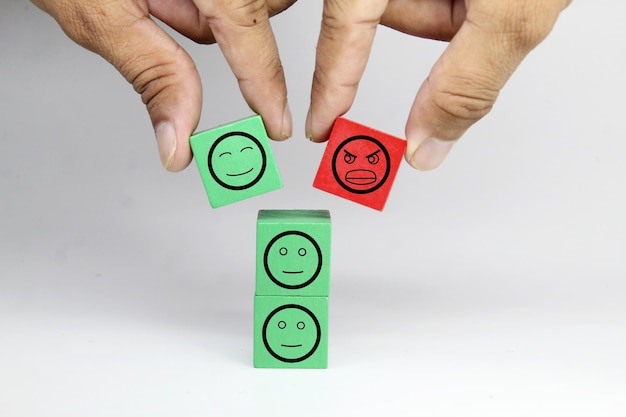 Una persona poniendo un cubo verde y rojo con un cuadrado rojo con un cuadrado verde con una carita sonriente.