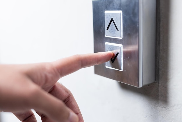 Persona presionando el botón del ascensor seleccionando el piso en un edificio de oficinas moderno