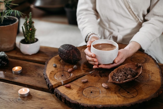 Persona que da cacao ceremonial en taza de bebida de chocolate vista superior