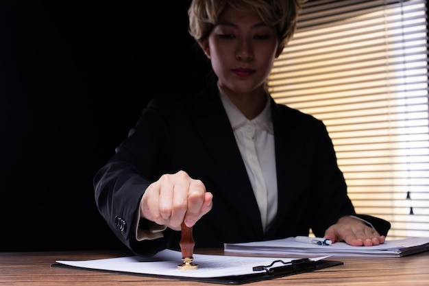 Persona que firma el documento de aprobación del certificado del acuerdo legal en el cargo con bolígrafo y sello. La autoridad aplica la ley para hacer el papeleo del contrato por medio de un escribano público o un espacio de copia de un abogado oficial.