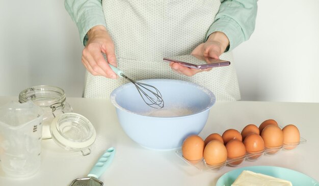 Persona que hornea usando una aplicación móvil para encontrar la receta