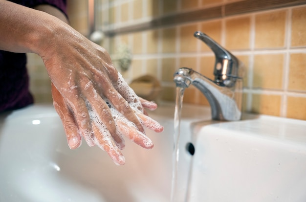 Persona que se lava las manos en el baño