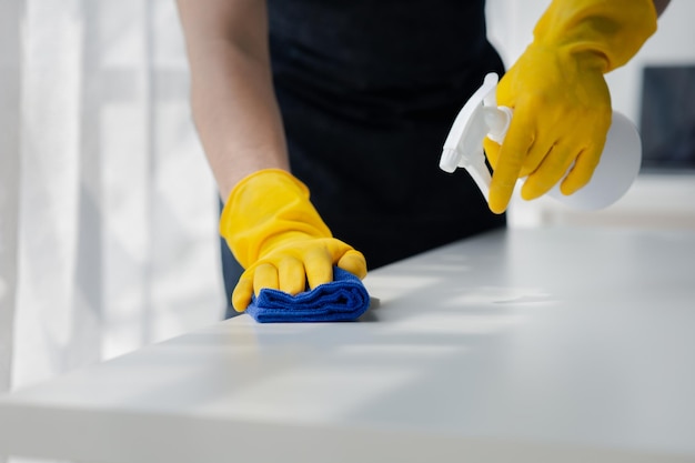 Persona que limpia la habitación El personal de limpieza está usando paño y rociando desinfectante para limpiar el escritorio en la habitación de la oficina de la empresa El personal de limpeza Mantiene la limpieza en la organización