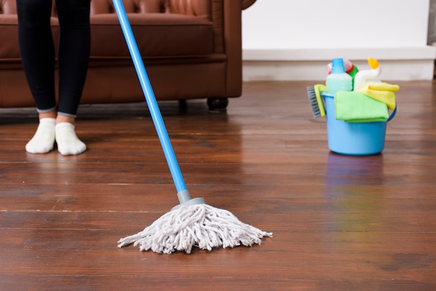 Foto persona que limpia el piso de madera en casa