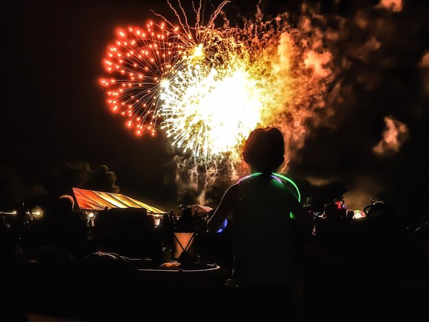 Foto persona que mira un espectáculo de fuegos artificiales durante la noche