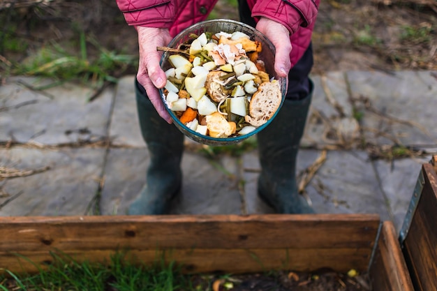 Foto persona que pone en un compostor algunos residuos de cocina como verduras, frutas, cáscaras de huevo, café para clasificar y hacer biofertilizante