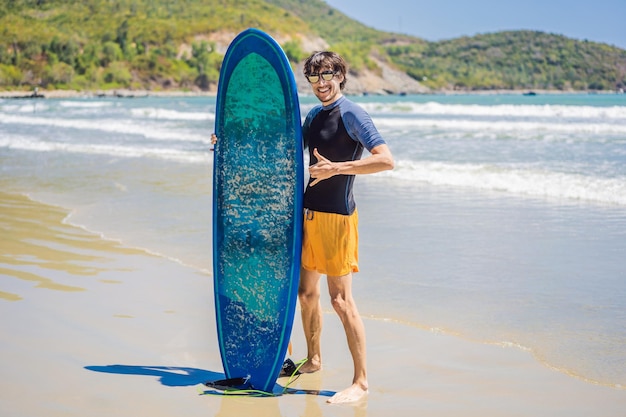 Persona que practica surf que sostiene una tabla de surf en la playa