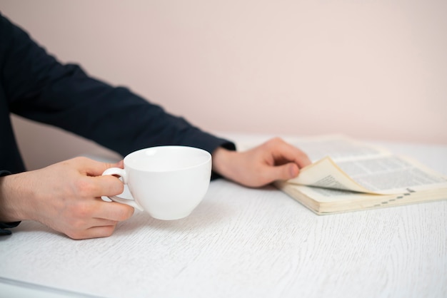 Una persona que se relaja en casa, lee un libro y bebe té, descansa por la noche.