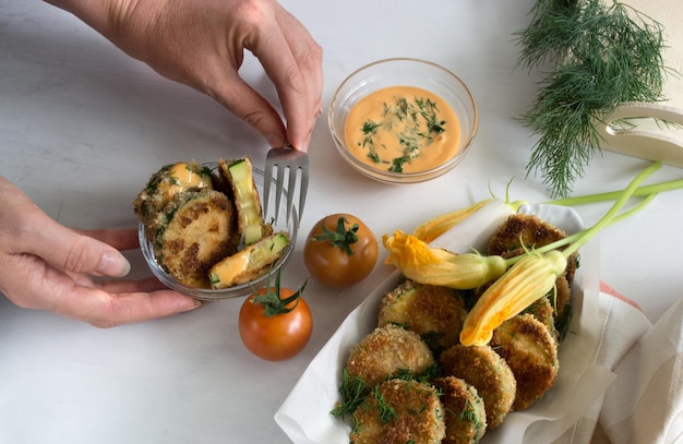 Persona que sirve calabacín frito empanizado con tomate y salsa. Foto de alta calidad