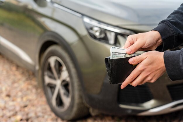 La persona que sostiene una billetera en las manos se encuentra frente al préstamo del seguro del automóvil y compra el concepto de financiación del automóvil