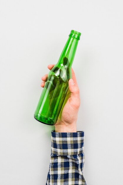 Foto persona que sostiene la botella de vidrio vacía sobre fondo blanco