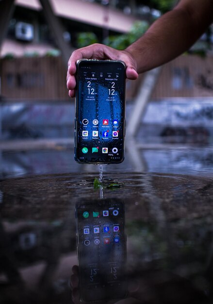 Una persona que sostiene una foto de un teléfono inteligente mojado