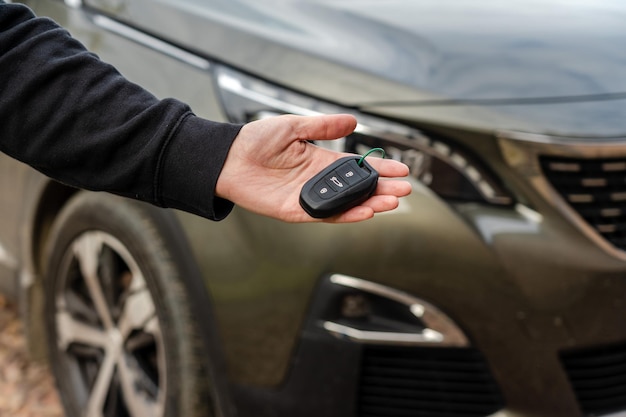 La persona que tiene la llave del auto en la mano se encuentra frente al préstamo del seguro del auto y compra el concepto del auto