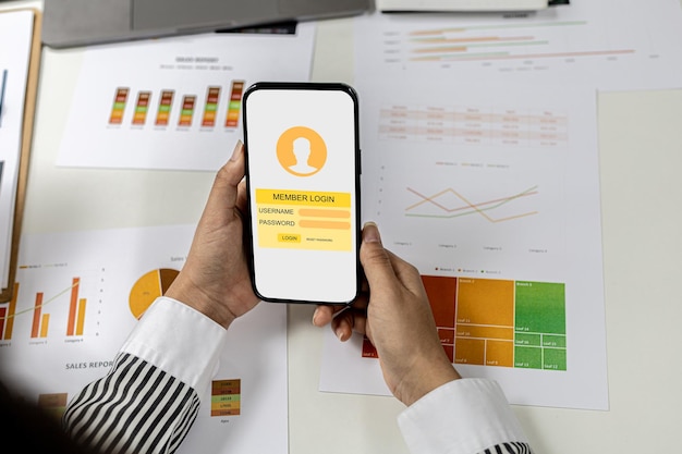 Persona que tiene un teléfono móvil en la pantalla de inicio de sesión de miembros, un empresario va a acceder al sistema de membresía de la empresa, verifica la información de las partes. en la empresa que está en el sistema.