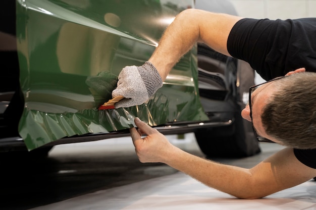 Foto persona que trabaja en la rotulación de automóviles.