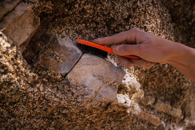 Una persona que usa un cepillo para limpiar una roca Motif Climbing