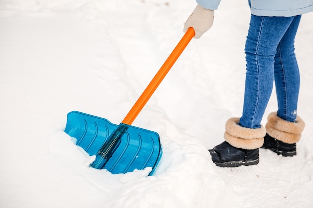 Una persona que usa una pala de nieve limpia la carretera o el patio de recreo de la nieve