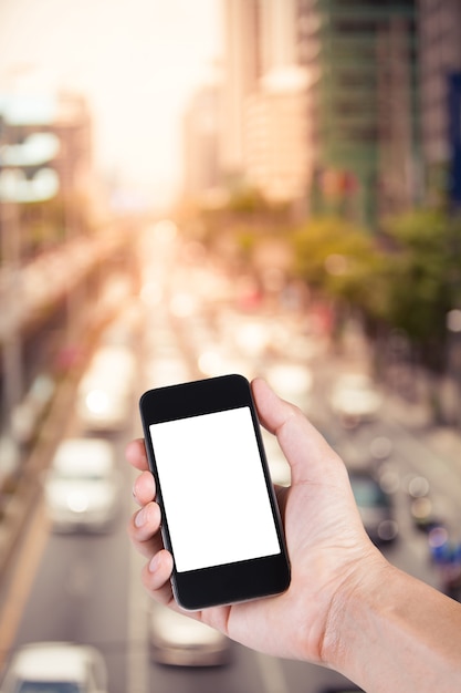 Foto persona que usa el sostenedor blanco de la pantalla del smartphone en la mano con borroso del atasco en la calle de la ciudad en bangkok tailandia.